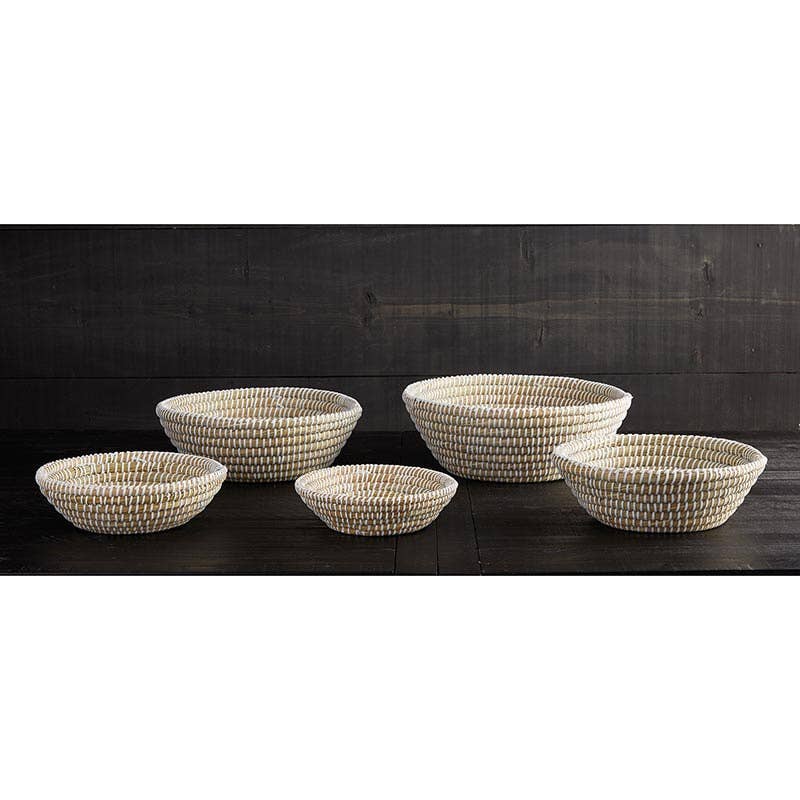 Set of five woven baskets on a dark wooden surface with a dark wooden wall background.